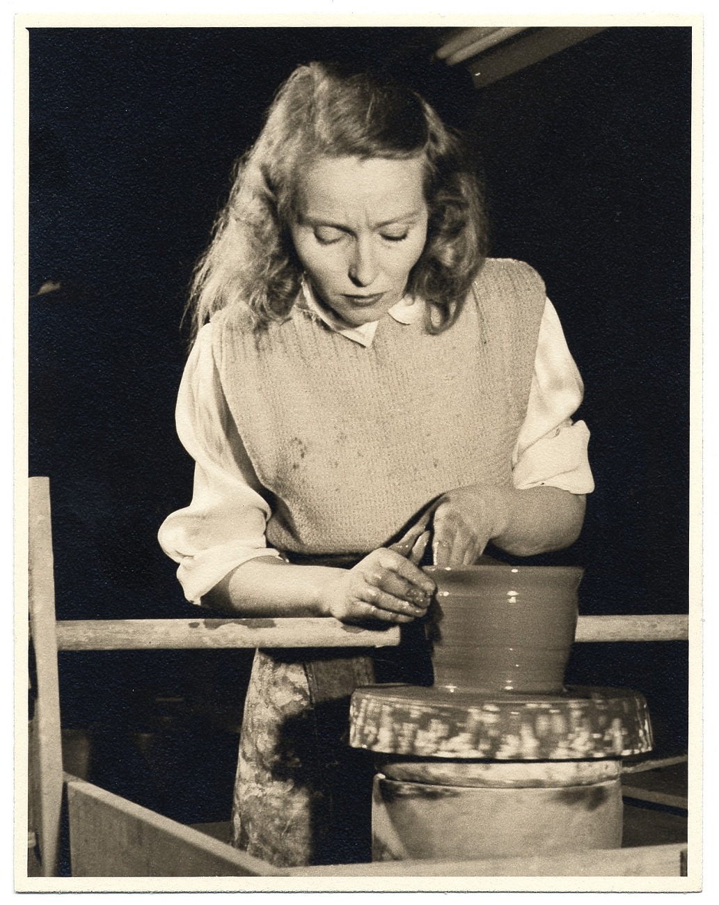Sepia-toned photograph of Edith Heath working on the potery wheel.