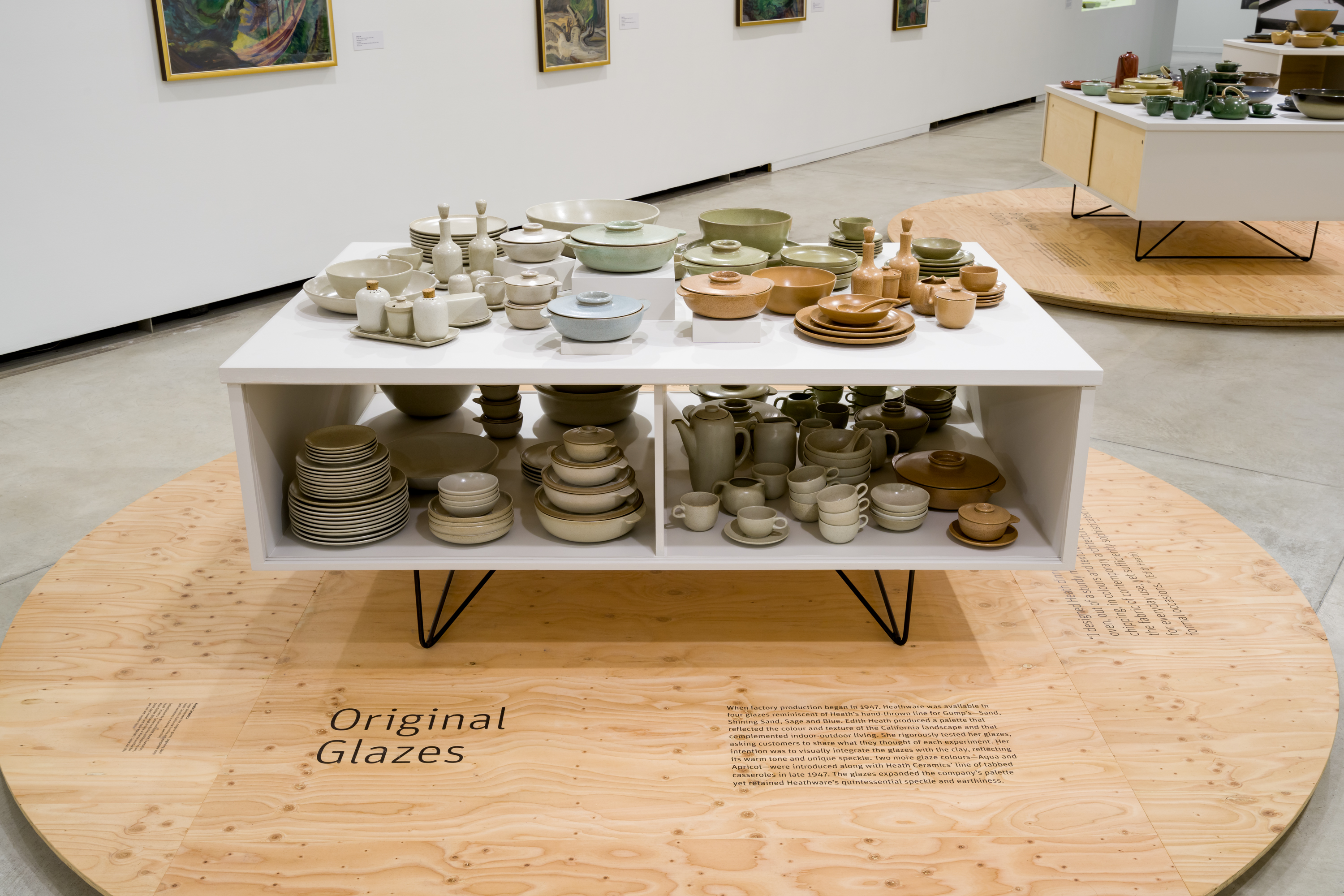 Dinnerware in light green, light blue, light orange and beige, displayed in a Conover cabinet.
