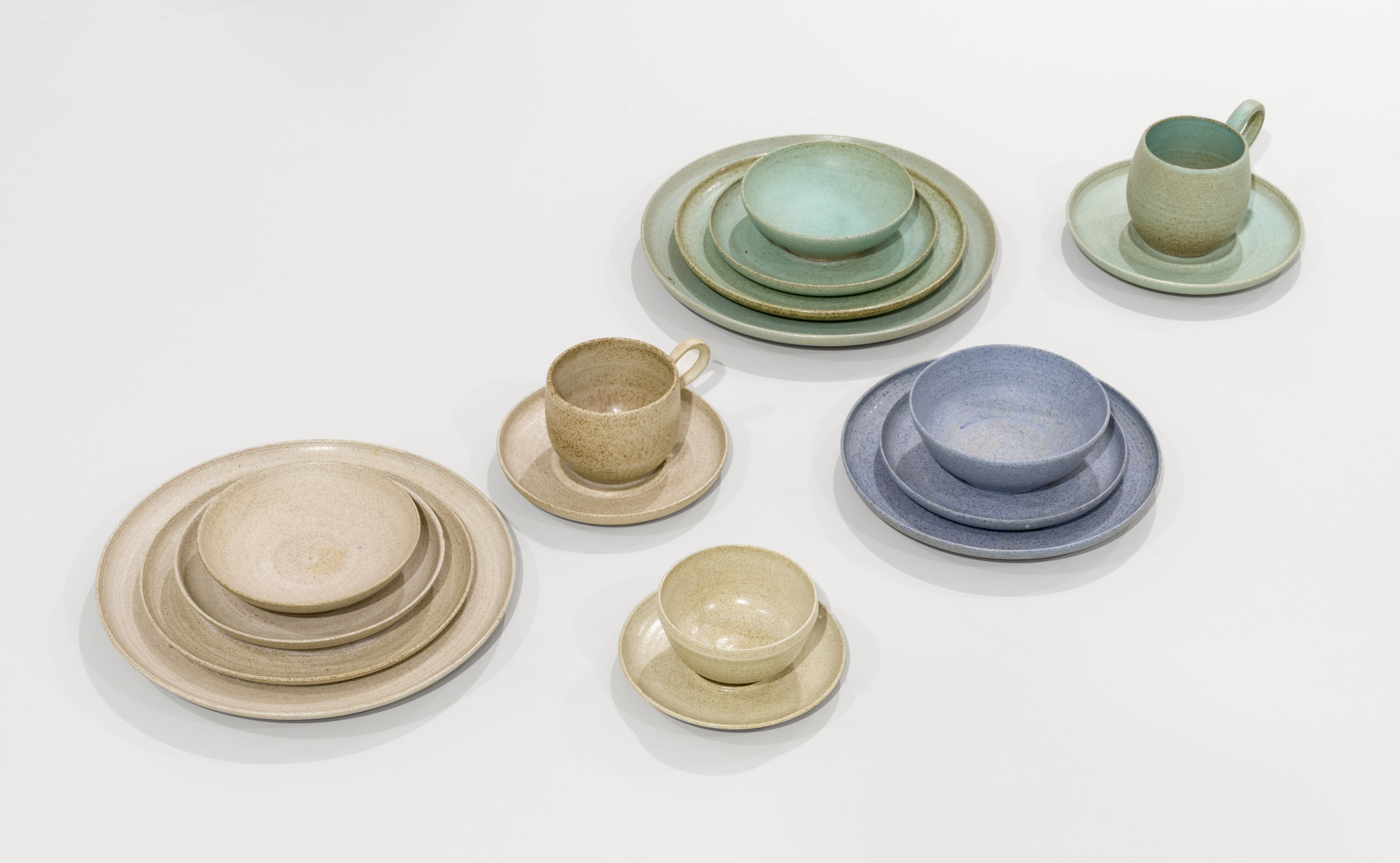 Photograph of pastel-coloured dinnerware sets displayed on a white surface.